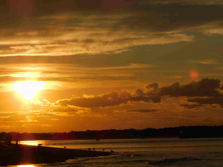 Sunset over the beach, with the silhouette of a person in front.